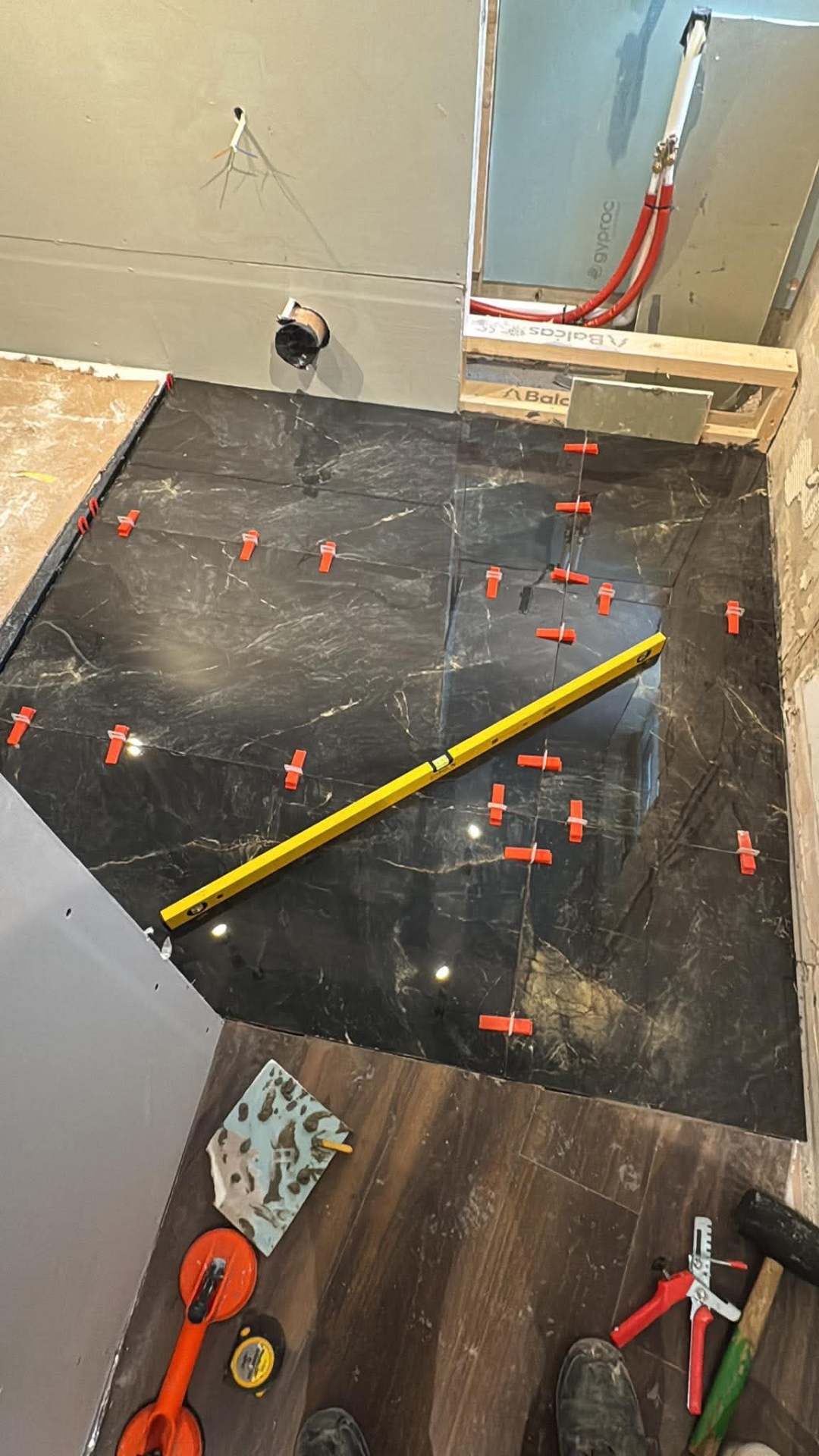 Marble shower wall — clips holding tiles flush