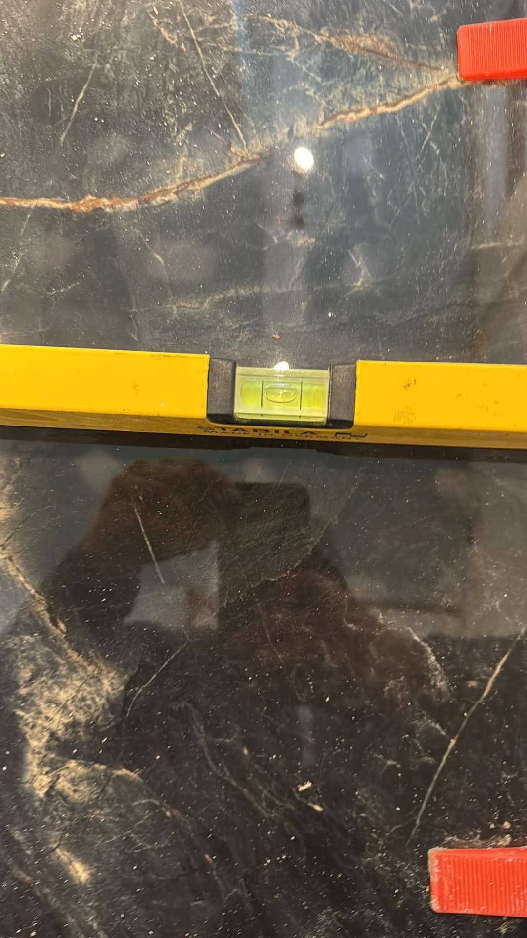 Yellow level on dark marble feature wall during setting out